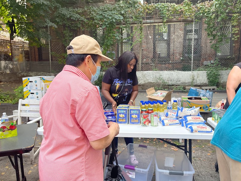 Volunteer sorting pantry items like pasta, oil, and canned goods at a table